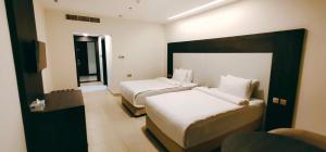 una camera d'albergo con due letti e una finestra di Manazil Aldar Hotel a Sohar