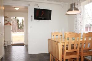 a dining room with a table and a tv on the wall at Malungs Camping in Malung