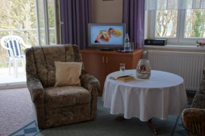 a living room with a chair and a table and a television at Hotel-Pension Seeblick in Kühlungsborn