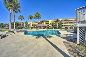 a swimming pool with palm trees in front of a building at Folly Beach Retreat with Pool Access and River Views! in Folly Beach