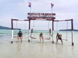 three women sitting on swings in the water on the beach at Sweet Time Bungalows in Koh Rong Sanloem