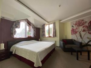 een slaapkamer met een bed, een stoel en ramen bij Ice Angels Hotel in Borovets