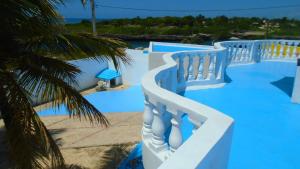 a blue swimming pool with a white fence and a palm tree at Guesthouse Villa La Isla in La Romana