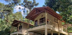 ein Haus mit einem Dach darüber in der Unterkunft Chalés Canto do Pavão in Visconde De Maua