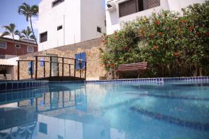 a swimming pool with a bench next to a building at Hotel Ilhas da Grécia in Guarujá +58 photos
