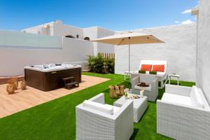 a patio with white chairs and an umbrella at HD Parque Cristobal Tenerife in Playa de las Americas