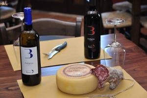 Agriturismo Polla في Camporgiano: طاولة مع زجاجتين من النبيذ وقطعة من الجبن