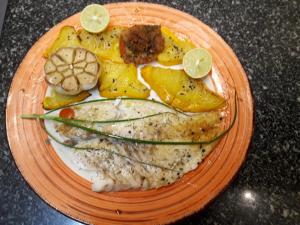 un piatto arancione di cibo con pesce e frutta di RIAD SAINT FRANCOIS & SPA a Rodrigues Island