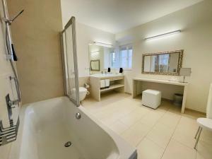 a bathroom with a tub and a toilet and a sink at Schlossparkhotel Mariakirchen in Arnstorf