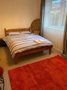 a bed in a bedroom with a window and a rug at Nice double and single rooms in the quiet area with excellent shared facilities in Plymouth