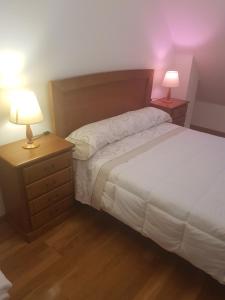 sypialnia z łóżkiem i 2 szafkami nocnymi z lampkami w obiekcie Apartamentos Burela w mieście Burela de Cabo