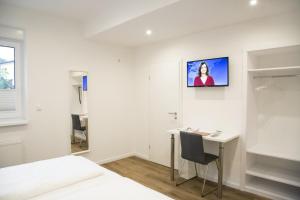 a bedroom with a desk and a tv on the wall at Main Motel in Dorfprozelten