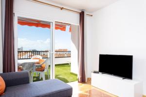 a living room with a television and a balcony at Home2Book Paradise Costa Adeje, Pool in Playa Fañabe