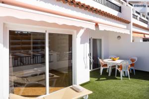 un patio con césped verde, mesa y sillas en Home2Book Paradise Costa Adeje, Pool, en Playa Fañabe