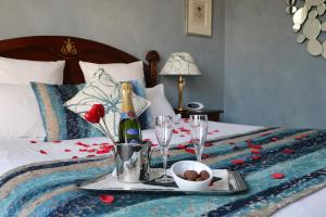 a tray with wine glasses and a plate of food on a bed at Hotel D'haussonville in Nancy