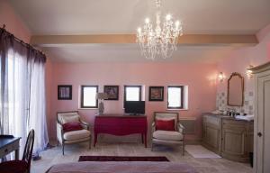 1 dormitorio con paredes rosas y lámpara de araña en Le Pré de l'Aube, en Montjoyer