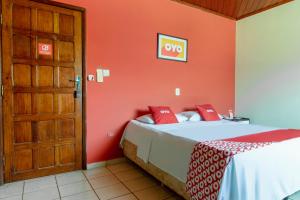 a bedroom with a bed with red walls and a door at OYO New Anápolis Hotel, Imperatriz in Imperatriz