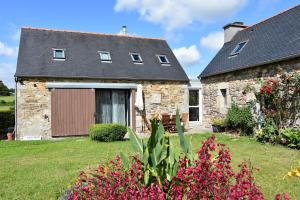 una casa in pietra con fiori nel cortile di Keryanti Domaine de Lesleac'h a Plouégat-Moysan