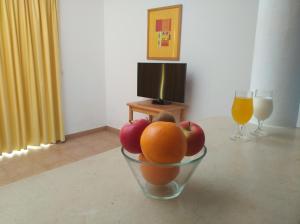 uma taça de fruta numa mesa com dois copos de laranjas em Club House CVL na Praia da Luz