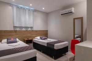 福塔莱萨Mega Aeroporto Hotel Apenas 1 km de distância do Aeroporto de Fortaleza的一间卧室，有两张床和一把红椅子