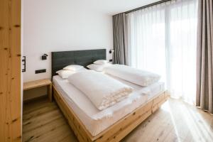 Un dormitorio con una cama grande con sábanas y almohadas blancas. en Schloss Auer, en Tirolo