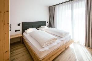 una camera da letto con un grande letto con lenzuola e cuscini bianchi di Schloss Auer a Tirolo
