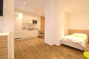 a white bedroom with a bed and a kitchen at Appartement Haberl in Bruck an der Mur