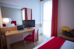 a hotel room with a desk with a computer and a bed at Hotel Remilia in Reggio Emilia