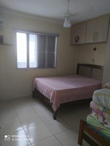 a bedroom with a pink bed and a window at Praia grande canto do forte top in Praia Grande