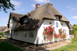 a thatched cottage with flowers on the side at Hotel Seiler Hof Keitum garni in Keitum