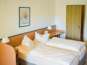 um quarto com uma cama com lençóis brancos e almofadas em WAGNERS Hotel im Frankenwald em Steinwiesen