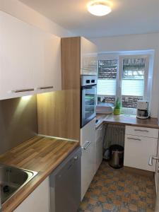 una cucina con mobili bianchi e un lavandino di Isartaler Hoamat Haus a Mittenwald