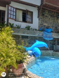 a pool with two dolphins in the water at Chalé dos Coelhos in Porto Seguro