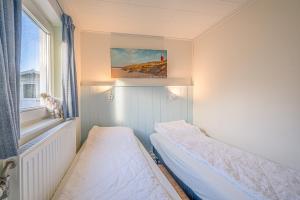 una piccola camera con due letti e una finestra di Vredelust 57 a De Koog