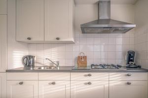 a kitchen with white cabinets and a stove top oven at Vredelust 57 in De Koog +3 photos