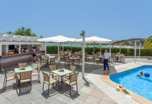a patio with tables and chairs and a swimming pool at Roc Portonova Apartaments in Palmanova