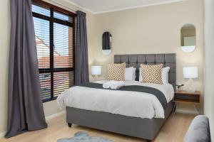a bedroom with a large bed and a window at Island Club Luxury Apartments in Cape Town