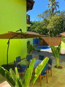 eine Terrasse mit einem Tisch, Stühlen und einem Sonnenschirm in der Unterkunft The Madalena Pousada in Imbassai