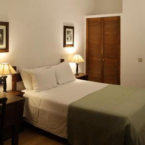 a bedroom with a large white bed with two lamps at Hotel Portofoz in Porto