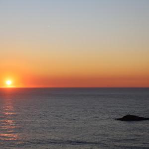 a sunset over the ocean with a rock in the water at Hotel Portofoz in Porto