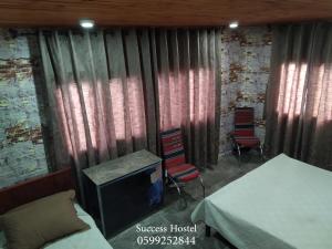 um quarto com uma cama e duas cadeiras e uma televisão em Success Hostel em Nablus