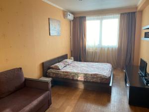 a bedroom with a bed and a couch and a window at Apartments on Otradnaya and Kho Shi Mina in Ulyanovsk