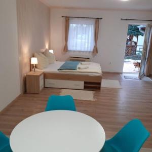 Pokój z łóżkiem i 2 niebieskimi krzesłami w obiekcie Apartments Annamaria w Hévízie