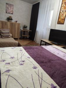 una camera con un letto con una coperta viola e bianca di Apartment on Sobornaya 58 a Chmel'nyc'kyj