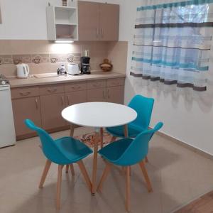 kuchnia ze stołem i niebieskimi krzesłami w obiekcie Apartments Annamaria w Hévízie