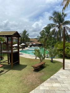 ein Resort mit einem Pool, einer Bank und Palmen in der Unterkunft Muro alto Bangalô pé na areia in Porto De Galinhas