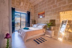 a bedroom with a large bed and a balcony at Fiftyfour West Boutique Living in Għarb
