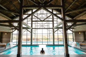 a person sitting in a swimming pool with a large window at Quinta Da Comporta - Wellness Boutique Resort in Comporta