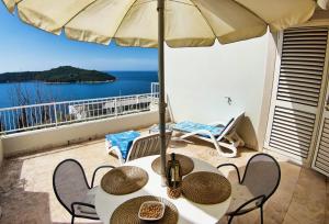 a table and chairs with an umbrella on a balcony at Sipa Apartments in Dubrovnik