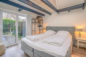 a bedroom with a large bed and a window at Zee van Tijd in De Koog